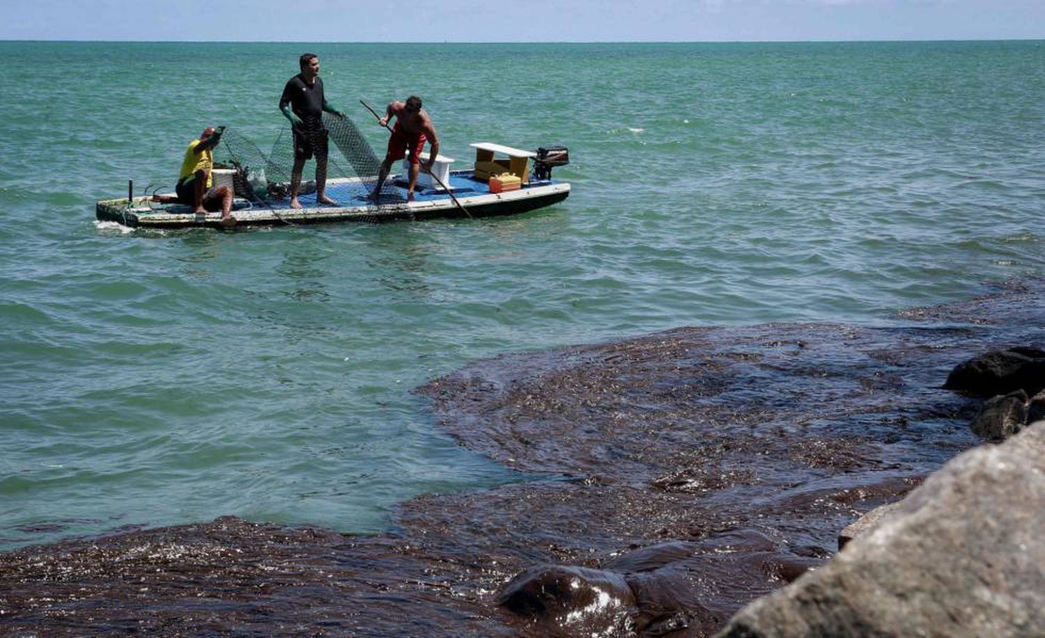 Pescadores recolhem óleo na praia de Janga, em Paulista, Pernambuco.