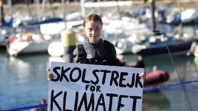 Greta Thunberg segura um cartaz onde se pode ler "Skolstrejk för klimatet" (en sueco, greve escolar pelo clima), em sua chegada a Lisboa.