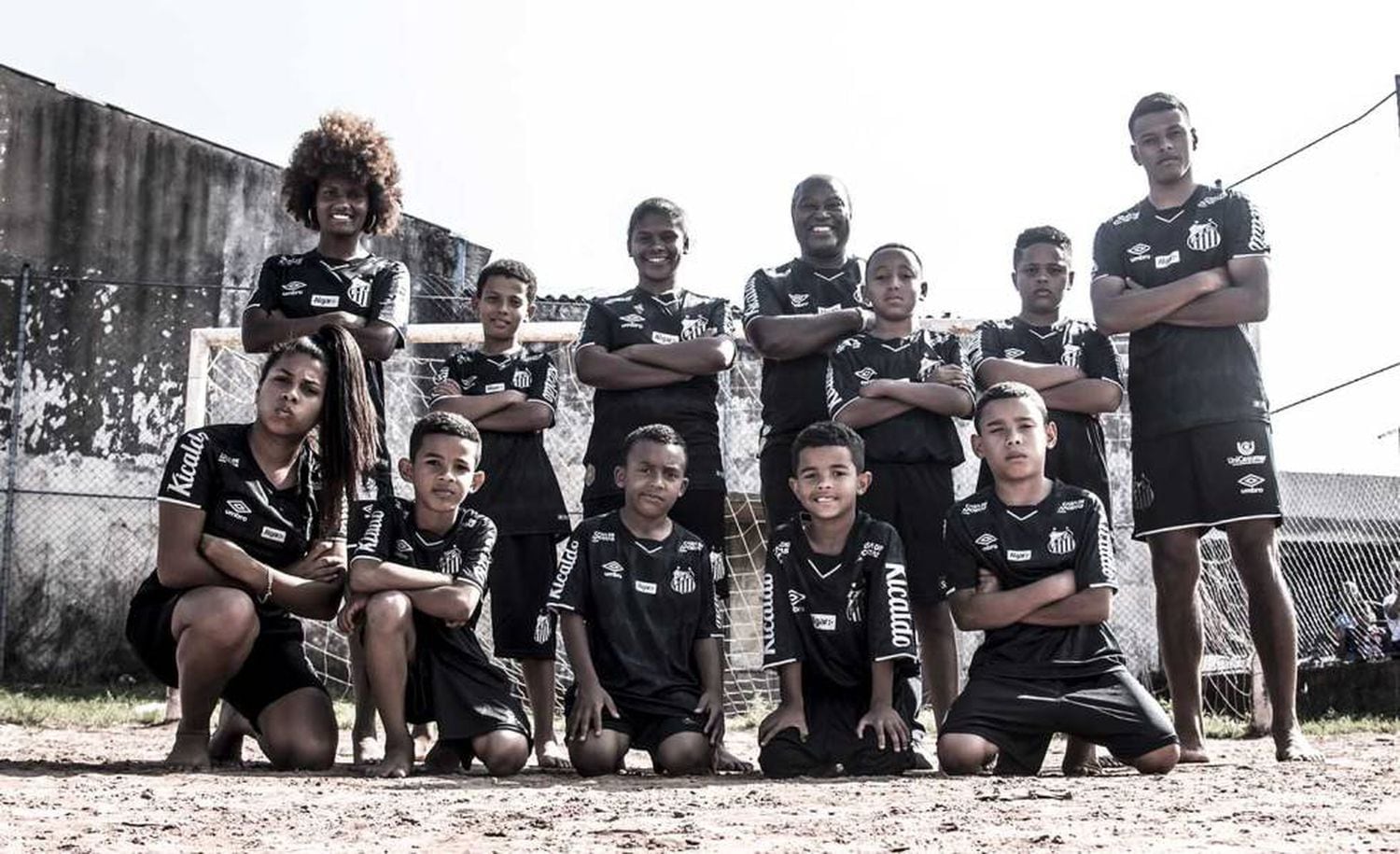 Maria Dias, Edu e Taílson com crianças de comunidade em Praia Grande na campanha de lançamento do terceiro uniforme.