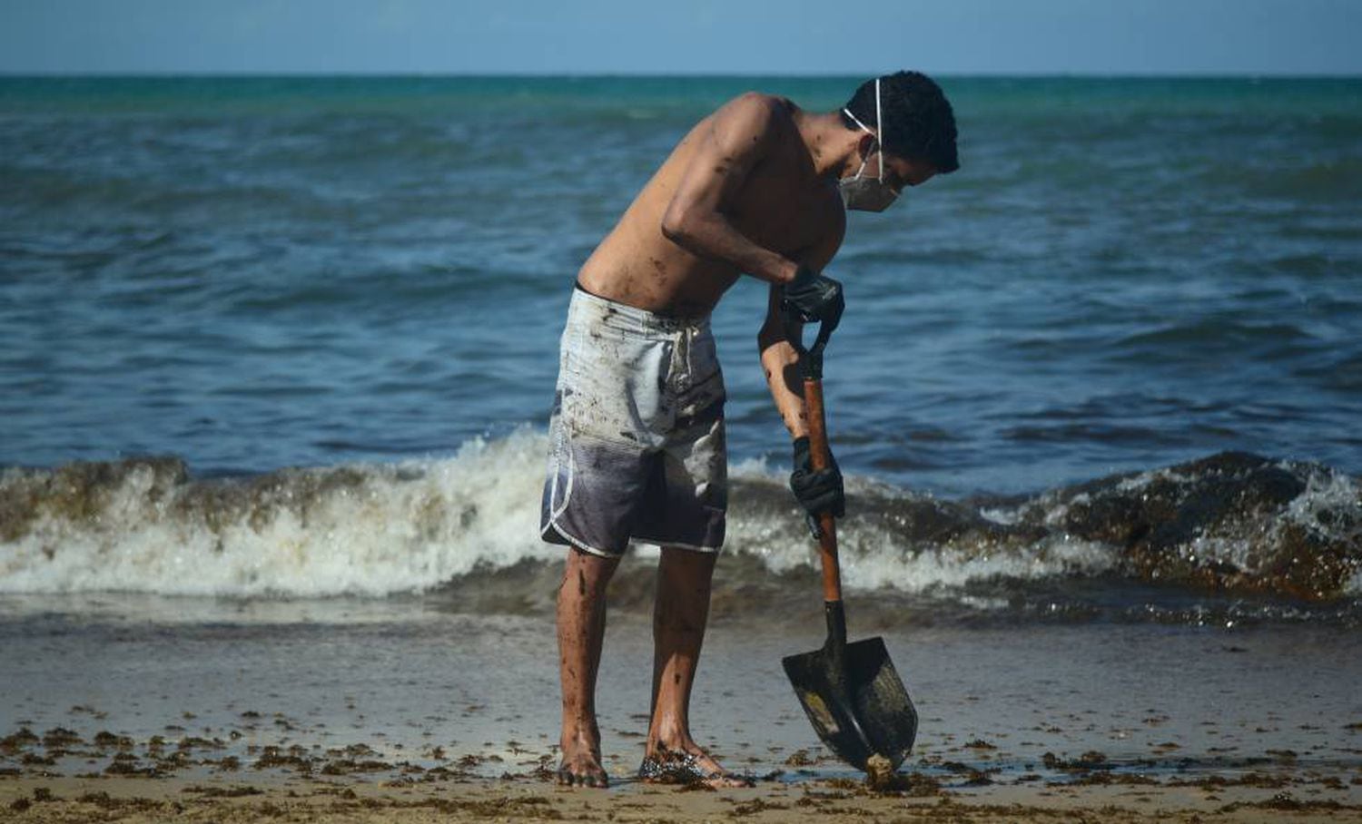 Jovem retira na terça-feira o óleo que atingiu praia de Itapuama, no litoral sul de Pernambuco.