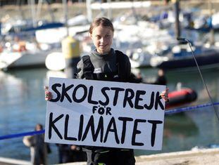 Greta Thunberg segura um cartaz onde se pode ler "Skolstrejk för klimatet" (en sueco, greve escolar pelo clima), em sua chegada a Lisboa.